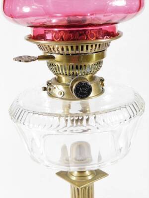 A late 19thC oil lamp, with clear chimney, fluted cranberry glass shade and glass reservoir, on a brass column and stepped foot, 74cm H. - 2