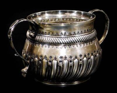 A Victorian silver two handled caudle cup, the shaped circular body partially gadrooned with S scroll handles, with plain base, London 1889, 9cm H, 5oz.