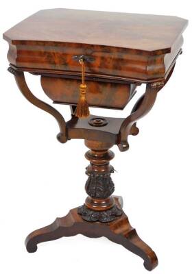 A mid 19thC mahogany sewing table, the inverted rectangular canted top with a flame quarter veneer, revealing various interior lidded and open sections, above a heavily carved acanthus leaf stem, on a tricorn platform base terminating in scroll feet, c184