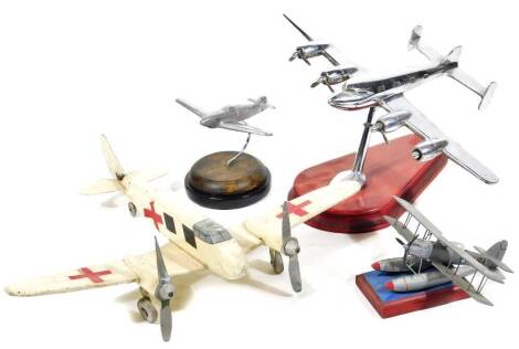 A chrome plated Art Deco design desk model of an aeroplane, on a shaped plinth base, 18cm H, another smaller, a wooden figure of an air ambulance, etc. (a quantity)