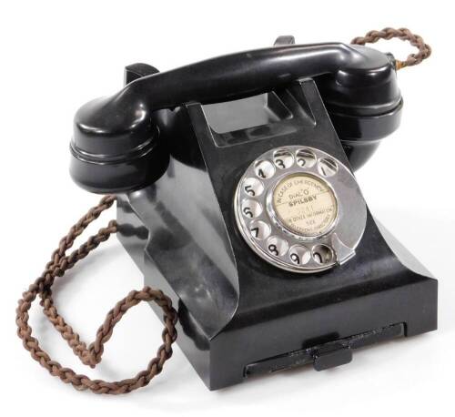 A 20thC black Bakelite telephone, with shaped receiver attached by a wire, with a articulated chrome front dial and drawer, 16cm W.