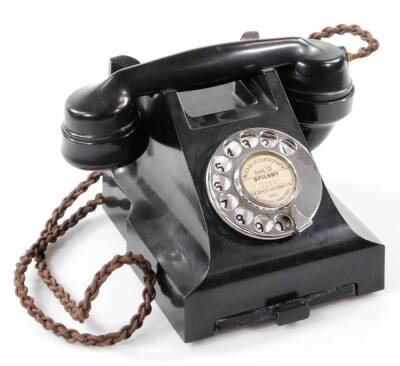 A 20thC black Bakelite telephone, with shaped receiver attached by a wire, with a articulated chrome front dial and drawer, 16cm W.