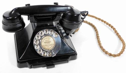 A 20thC black Bakelite telephone, with shaped receiver attached by a wire, with articulated front chrome dial and drawer, 20cm W.