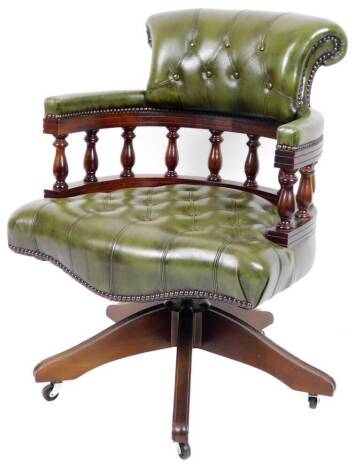 A captain's swivel office chair, with shaped green leather back, C scroll arms and serpentine studded seat, on a swivel stem terminating in five scroll legs with castors, 88cm H.