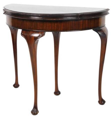 An early 20thC mahogany fold over card table, with a pie crust border broken by carved flowers on cabriole legs terminating in shell feet, with a baize lined interior, when closed 74cm H, 85cm W, 42cm D.