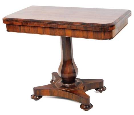 An early 19thC rosewood fold over card table, the baize lined rounded top on a turned octagonal stem and inverted platform base, terminating in compressed feet, when closed 72cm H, 90cm W, 47cm D.