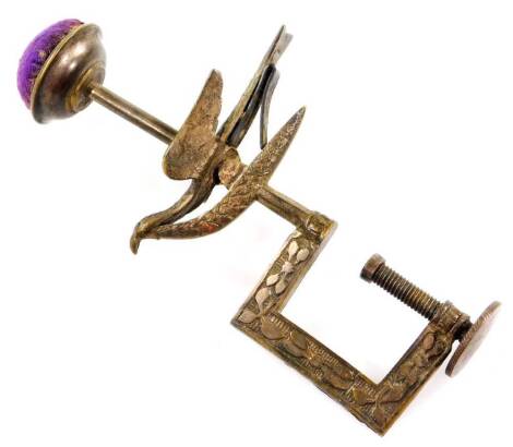 An Edwardian metal sewing clamp, with pin cushion top, bird centre and G-clamp articulated base, 14cm H.