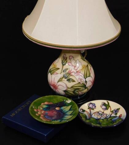 A Moorcroft table lamp and saucer, 6cm W, each decorated with flowers, and another saucer Hepatica pattern. (3)