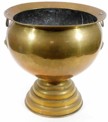 A large early 20thC brass vessel, the circular body, flanked by ring handles set with oval emblems on an inverted stem and stepped base, 43cm H, 42cm Dia. (AF)