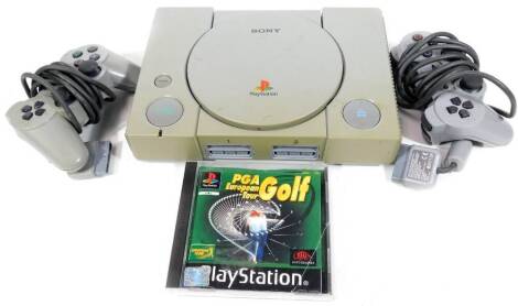 A Playstation 1 games console, 26cm W, with two controllers, further accessories and a PGA European Tour Golf game.