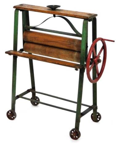 A early 20thC child's toy mangle, with wooden mounts and metal frame, with articulated circular side handle on wheels, 49cm H.