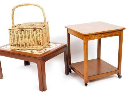 A wicker basket, with fixed C shaped handle, with fitted interior, 48cm H, an oak two tier trolley on wheels and a teak coffee table with six sectional tile top. (3)