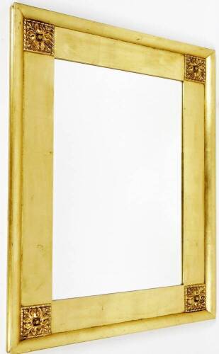 A late 20thC gilt wood mirror, of rectangular form, with raised floral spandrels and bevel glass, 77cm x 100cm.