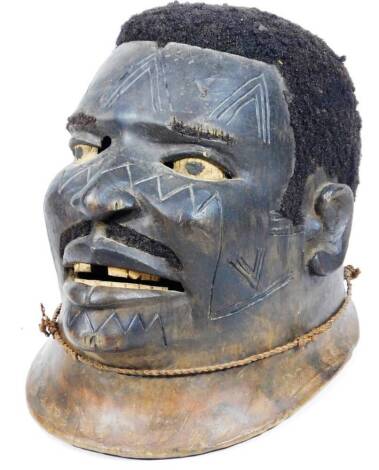 A Macindi Portuguese settler head, formed as an African gentleman, reputed to have original hair, with a partially carved wooden face on an oval base with lower stringing, 27cm H.