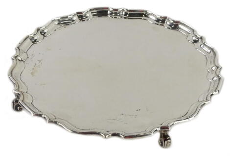 A George VI silver salver, with a pie crust border, on scroll cast feet, Birmingham 1932, maker H E & Co, stamped capital, 17¾oz, 26cm D.