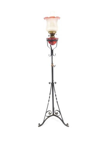 A Victorian duplex standard oil lamp, with a ruby glass reservoir, glass chimney and Art Nouveau floral frosted clear to cranberry glass shade, raised on a cast iron telescopic stand, raised on three scrolling feet, 164cm H.