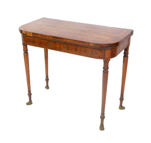 A Regency rosewood and yew wood cross banded demi-lune fold over card table, raised on turned legs, on brass paw feet, 76.5cm H, 91cm W, 45cm D.