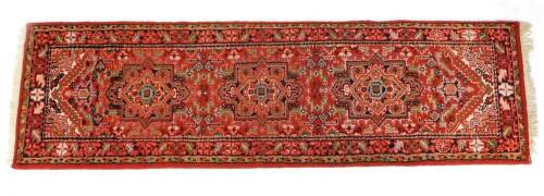 A Caucasian runner, decorated with three guls, floral and foliate motifs against a red ground,. 257cm x 72cm.