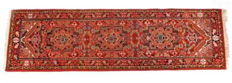 A Caucasian runner, decorated with three guls, floral and foliate motifs against a red ground,. 257cm x 72cm.