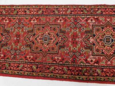 A Caucasian runner, decorated with three guls, floral and foliate motifs against a red ground,. 257cm x 72cm. - 3