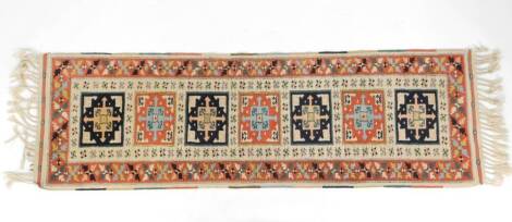 A Turkish Oushak runner, decorated with seven rectangular geometric motifs, within floral borders, against a cream ground, 246cm x 69cm.