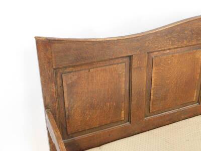 A 19thC oak settle, with a four panelled back, scrolling arms, with over stuffed seat, raised on turned legs, 183cm W. - 2