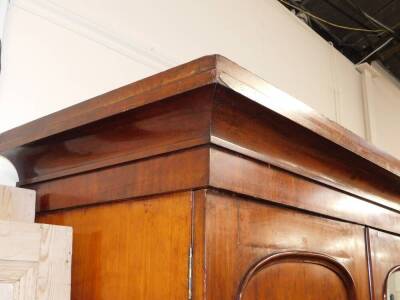 A Victorian plum pudding mahogany compactum wardrobe, the outswept pediment over three doors, the central door inset with glass, opening to reveal four slides above two short over two long drawers, flanked to the right by a hanging rail and further drawer - 3