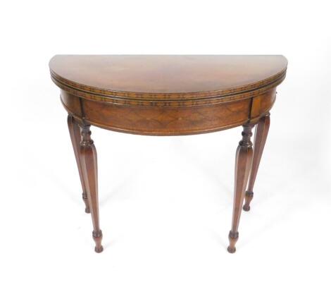 A George IV mahogany and line inlaid demi-lune fold over card table, with a cross banded and line inlaid freize, raised on turned and hexagonal tapering legs, on disc feet, 76cm H, 91cm W, 45cm D.