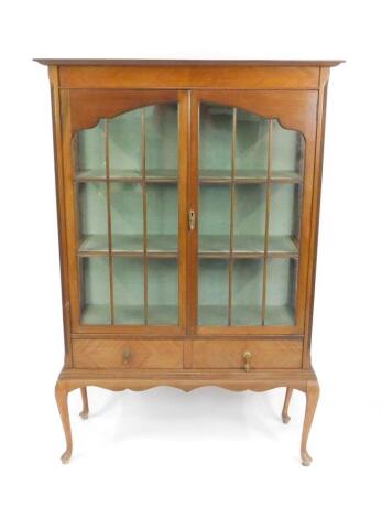 A Victorian mahogany display cabinet, the stepped outswept pediment over two glazed doors, opening to reveal two shelves, above two frieze drawers, raised on cabriole legs, 159cm H, 106.5cm W, 40cm D.