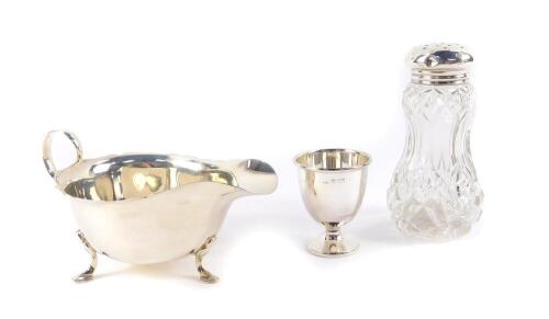 A silver sauce boat, raised on three hoof feet, Mappin & Webb, Sheffield 1990, a silver egg cup, Sheffield 1966, 4.75oz, and a cut glass sugar sifter with silver lid, Birmingham 1908. (3)