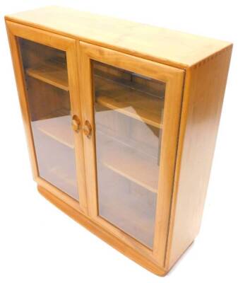 An Ercol light elm bookcase, with two glazed doors on concave plinth, 92cm W.