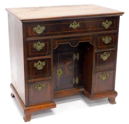 A mahogany and walnut crossbanded kneehole dressing table, in mid 18thC style, the rectangular top with a moulded edge, above a frieze drawer and seven further drawers around a kneehole with cupboard door, each with pierced brass mounts, on ogee bracket f