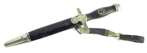 A German RLB Third Reich dagger, the handle applied with a badge with black enamel swastika (AF), with eagle and swastika guard, ebonised metal scabbard, the blade unstamped with leather belt attachment, 36cm L.