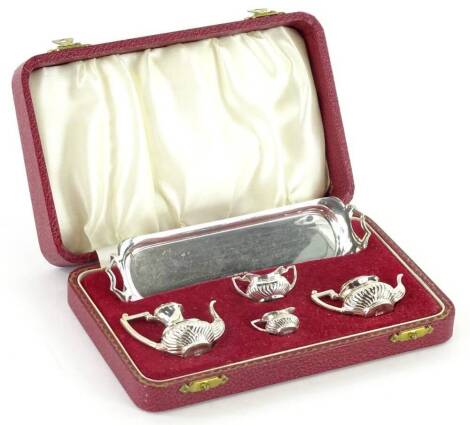 An Elizabeth II silver miniature four piece tea set, comprising rectangular two handled tray, tea pot, coffee pot, milk jug and sugar bowl, with part fluted decoration, 2oz, in original fitted case.