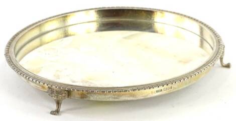 An Elizabeth II silver waiter, the raised border with crenellated edge on three tapering feet, headed by crowns, London 1987, 13¼oz, 19cm dia.