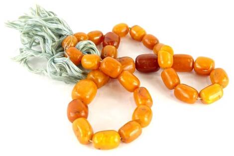 A butterscotch amber beaded necklace, with a mixture of oblong beads of varying sizes, the largest 2.5cm wide, the smallest 1.2cm wide, on string strand with tassel end, 117.6g all in. (AF)