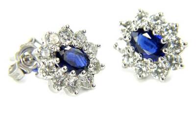 A pair of 18ct white gold sapphire and diamond cluster earrings, each set with central oval facetted sapphire, mid to dark blue, 5.5mm x 3.75mm x 2.25mm, approx 0.4cts each, surrounded by ten round brilliant cut diamonds, 2.25mm x 2.25mm, approx 0.05cts e