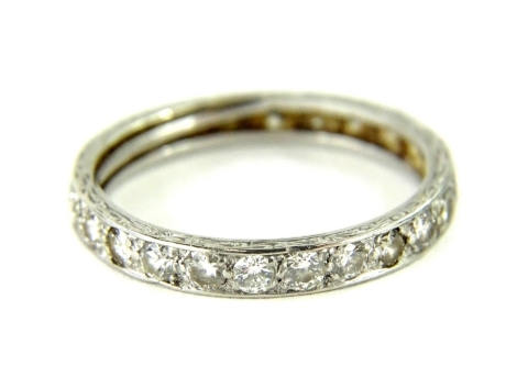 A diamond eternity ring, set with twenty five round brilliant cut diamonds, each 2.2 x 1.4mm, total estimated carat weight 1ct, in white metal setting, unmarked, with rubbed design outer band, ring size O, 2.9g all in.