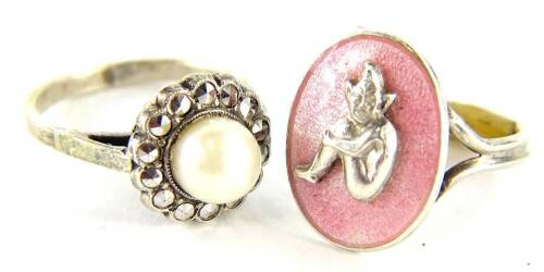 Two dress rings, to include a silver marcasite and cultured pearl cluster ring, with v shaped design shoulders, boxed, together with a silver plated and pink enamelled imp dress ring. (2)