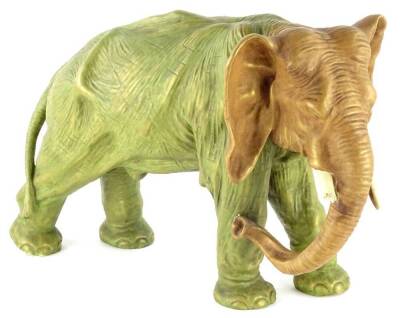 A late 19th/early 20thC porcelain figure of an elephant, in the manner of Royal Dux, with a green and gold glaze, (AF), 40cm L.