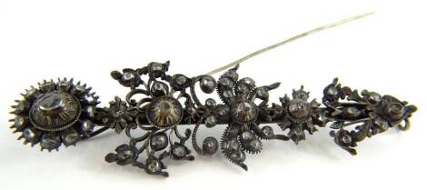 A Georgian steel brooch, of floral stem design, with flower head and leaves, set with white stones, on a single pin back, unmarked, boxed. (AF)