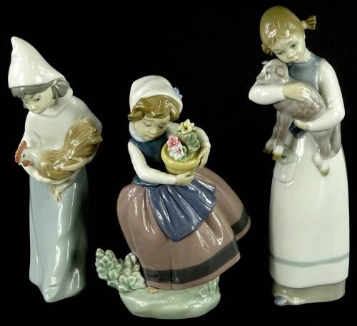 Three Lladro porcelain figurines, two modelled in the form of children with a cockerel and a lamb, the other a child with a basket, the largest 23cm H.