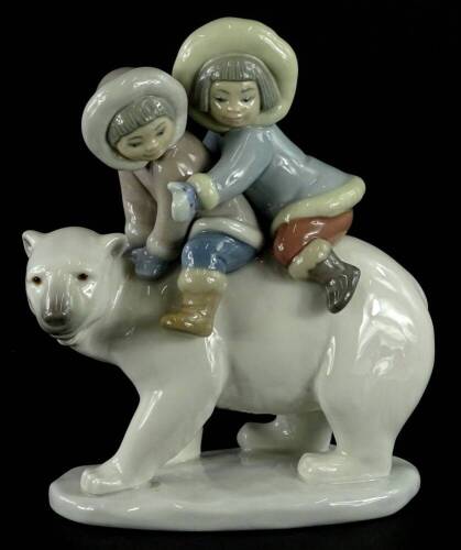 A Lladro porcelain figure of two children riding a polar bear, 15cm H.