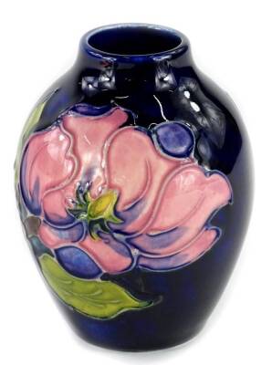 A Moorcroft pottery small vase, decorated with purple flowers on a navy ground, unmarked, 9cm H.