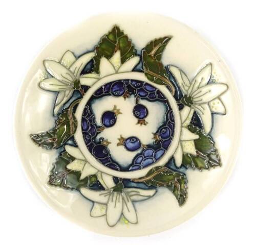 A Moorcroft pottery small pin tray, decorated with leaves, white flowers and berries, 12cm dia, boxed.