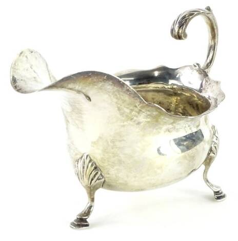 An Edwardian silver sauce boat, with scroll handle and three shaped legs, headed by shells, London 1901, 5¼oz.