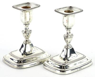 A George V silver rectangular candlesticks, each with beaded borders, loaded, Sheffield 1921, 15cm H.