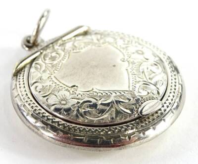 A George V circular silver powder compact, the hinged lid, containing a mirror, enclosing a powder puff, etc., engraved overall with flowers and leaves around a vacant cartouche with suspension loop, 3cm dia.