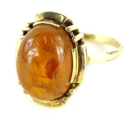 A modern amber dress ring, with oval cut amber, in claw raised basket setting, on a yellow metal band, marked 14K, ring size Q, 4.6g all in.