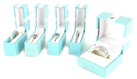 Five modern silver dress rings, to include three set with CZ stones, and two with blue and CZ stones, boxed. (5)